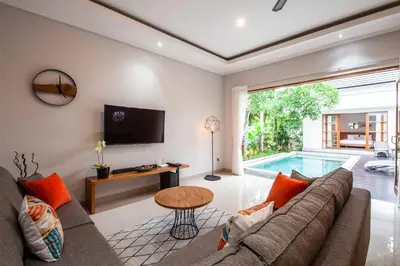 a living room with a couch and a tv and a pool at Villa Voyage 5 in Seminyak