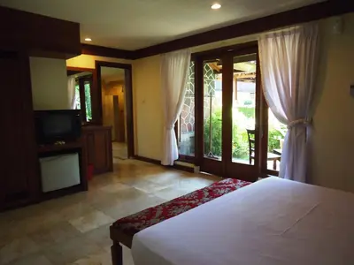 a bedroom with a bed and a tv and windows at Ananda Resort Seminyak in Seminyak