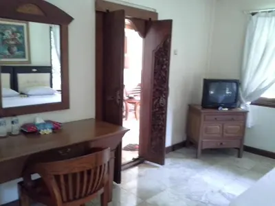 a room with a desk and a mirror and a television at Ananda Resort Seminyak in Seminyak