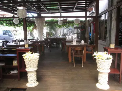 a restaurant with wooden tables and chairs and flowers at Ananda Resort Seminyak in Seminyak