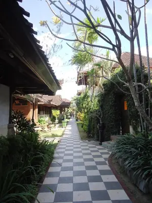 a walkway through a resort with trees and plants at Ananda Resort Seminyak in Seminyak