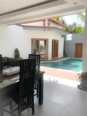 a dining room with a table and a swimming pool at Bali Villas Arta in Seminyak