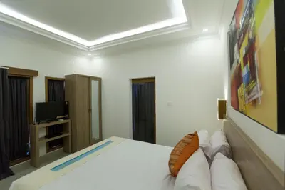 a bedroom with a white bed and a television at Bali Villas Arta in Seminyak