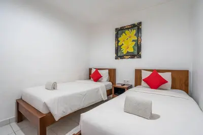 a room with two beds and a picture on the wall at Ganandra Stay Denpasar in Denpasar