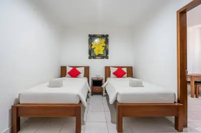 two beds in a room with white walls at Ganandra Stay Denpasar in Denpasar