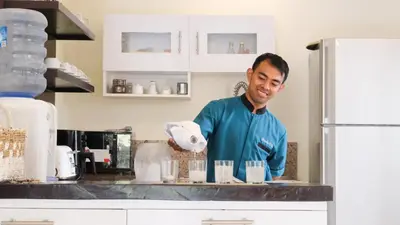 a man is standing in a kitchen preparing food at Amalia Swan Haven Villa Seminyak in Seminyak
