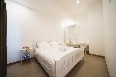a white bedroom with a white bed and a mirror at Umaja Villa in Seminyak