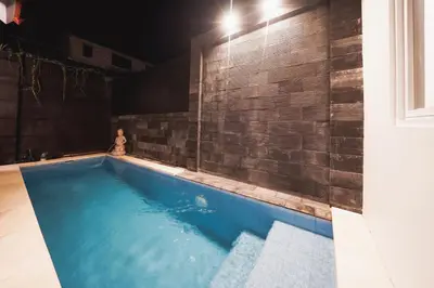 a swimming pool in a room with a brick wall at Umaja Villa in Seminyak