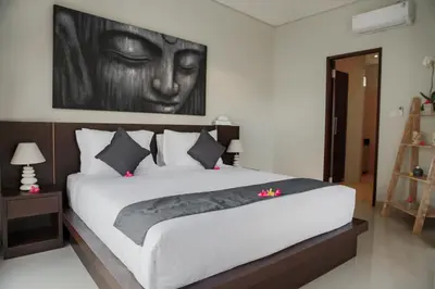 a bedroom with a large bed with a painting on the wall at Villa 66, 5 min walk to Double 6 beach in Seminyak