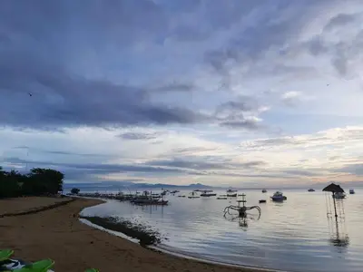a bike sitting in the water next to a beach at Genta House in Kuta