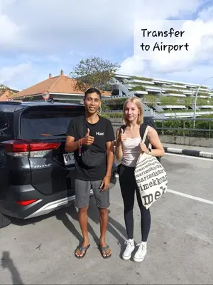 a man and a woman standing next to a car at Genta House in Kuta