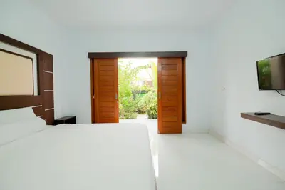 a bedroom with a bed and a flat screen tv at Kadek Bagus Guesthouse Denpasar Mitra RedDoorz in Kerobokan
