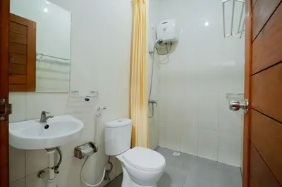 a bathroom with a toilet and a sink at Kadek Bagus Guesthouse Denpasar Mitra RedDoorz in Kerobokan