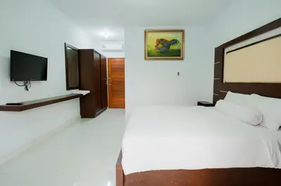 a bedroom with a bed and a flat screen tv at Kadek Bagus Guesthouse Denpasar Mitra RedDoorz in Kerobokan