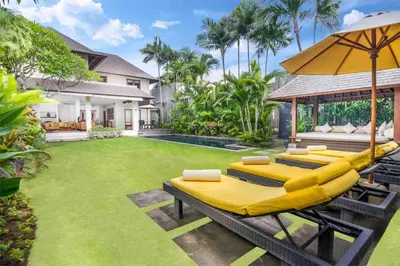 a backyard with a bunch of chairs and an umbrella at Serene Villas in Seminyak