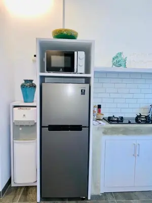 a refrigerator with a microwave on top of it in a kitchen at Casa Su Seminyak in Seminyak