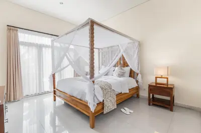 a bedroom with a canopy bed with white sheets at Saga Villas Legacy in Seminyak