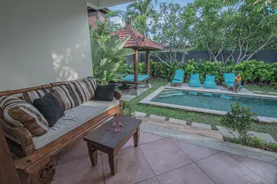a couch and a table next to a swimming pool at Leluhur 1 Private Pool Villa in Seminyak