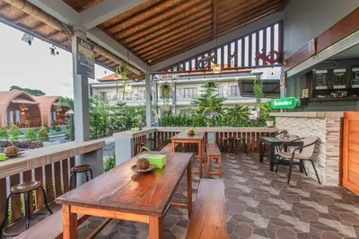 a restaurant with wooden tables and chairs on a patio at Mailaku House in Kerobokan