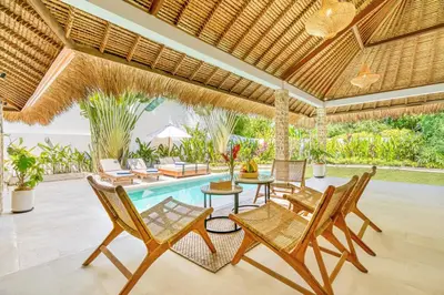 an outdoor patio with chairs and a pool at Villa Barcelona - Private 6 BDR Brand New Villa in Seminyak, Best Location, large Pool & Garden in Seminyak