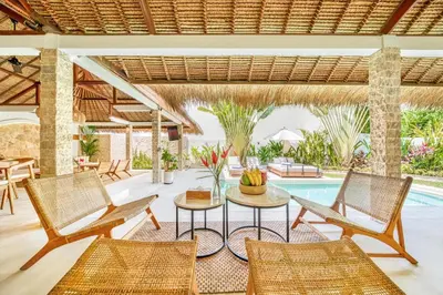 an outdoor patio with chairs and a table and a pool at Villa Barcelona - Private 6 BDR Brand New Villa in Seminyak, Best Location, large Pool & Garden in Seminyak