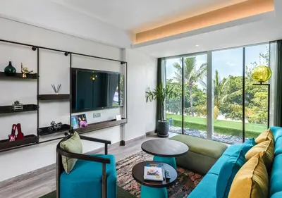 a living room with a blue couch and a tv at MAMAKA by Ovolo in Kuta