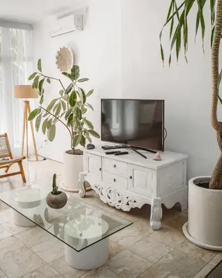 a living room with a tv and a white table at THE HIDDEN TREE CANGGU 100 meter to beach in Canggu