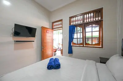a bedroom with a bed with blue slippers on it at Ceria Guesthouse Seminyak Mitra RedDoorz in Seminyak