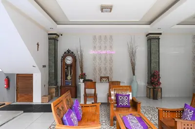a living room with chairs and a grandfather clock at Ceria Guesthouse Seminyak Mitra RedDoorz in Seminyak