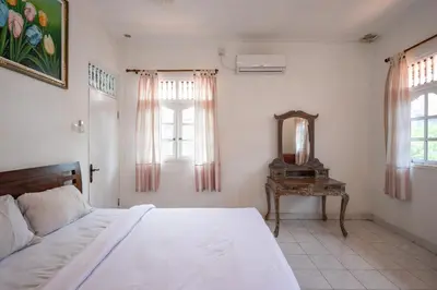 a bedroom with a bed and a mirror and a table at Ceria Guesthouse Seminyak Mitra RedDoorz in Seminyak