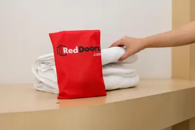 a person is reaching for a red door bag on a counter at KoolKost at Poppies Lane Street - Minimum stay 30 nights in Denpasar