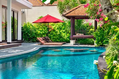 a swimming pool with a red umbrella and a chair at D&G Villas Nusa Dua in Nusa Dua