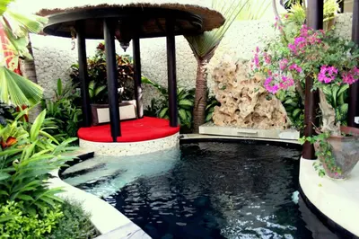 a koi pond with a red seat in a garden at Sandi Kala Villas in Kerobokan