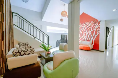 a living room with two chairs and a staircase at Balitone Guest House in Denpasar