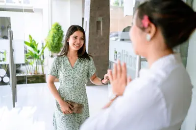 a woman standing in an office talking to a woman at Balitone Guest House in Denpasar