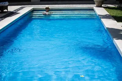 a man in a pool of blue water at Villa Alu Lima in Seminyak