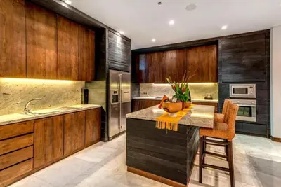 a kitchen with wooden cabinets and a kitchen island with orange chairs at Villa De Jiwa 495 Seminyak in Seminyak