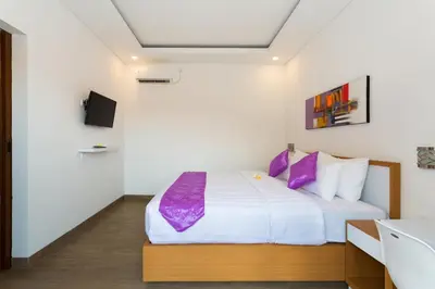 a bedroom with a large bed with purple pillows at Pondok Bobo Seminyak in Seminyak