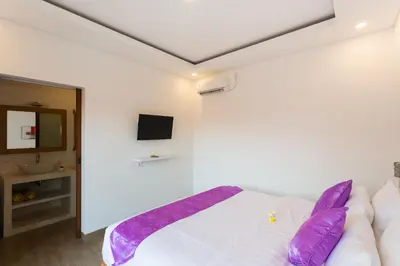 a bedroom with a white bed with purple pillows at Pondok Bobo Seminyak in Seminyak