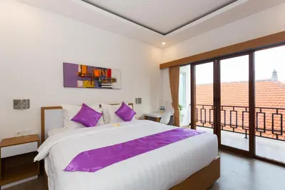 a bedroom with a large bed and a balcony at Pondok Bobo Seminyak in Seminyak