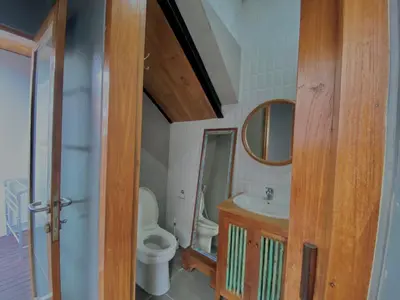 a bathroom with a toilet and a sink and a mirror at Ruang Tekuni in Legian