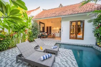 a villa with a swimming pool and two chairs at Villa Joli in Seminyak