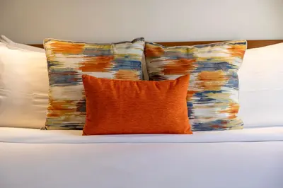 two pillows and an orange pillow on a bed at Villa Joli in Seminyak