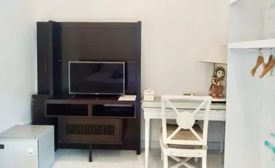 a living room with a tv and a desk with a television at NIKINIKO Beach House by Lolavillas - 100mts to the beach in Canggu