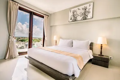 a bedroom with a large bed and a large window at ABISHA Resort Jimbaran in Jimbaran