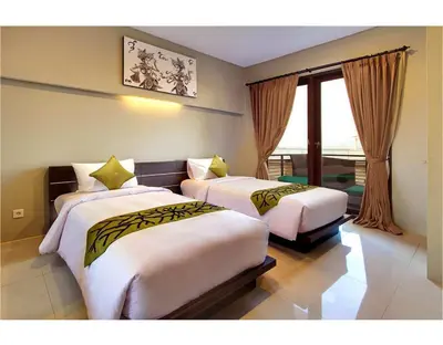 a hotel room with two beds and a window at ABISHA Resort Jimbaran in Jimbaran