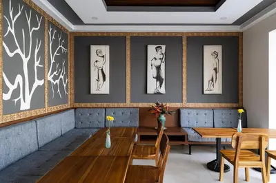 a dining room with a table and chairs and paintings on the wall at The Calna Villa Bali in Kuta