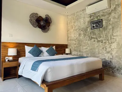 a bedroom with a large bed and a wall at The Calna Villa Bali in Kuta