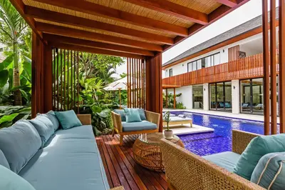 an outdoor patio with a couch and chairs and a swimming pool at THE BOTANICAL 6 BED LUXURY 900 meter from beach in Seminyak