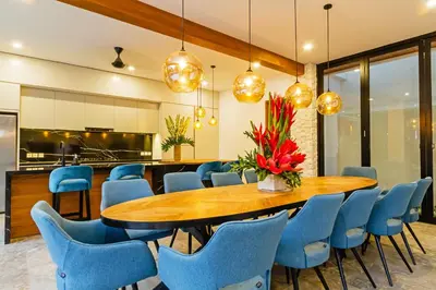 a dining room with a wooden table and blue chairs at THE BOTANICAL 6 BED LUXURY 900 meter from beach in Seminyak